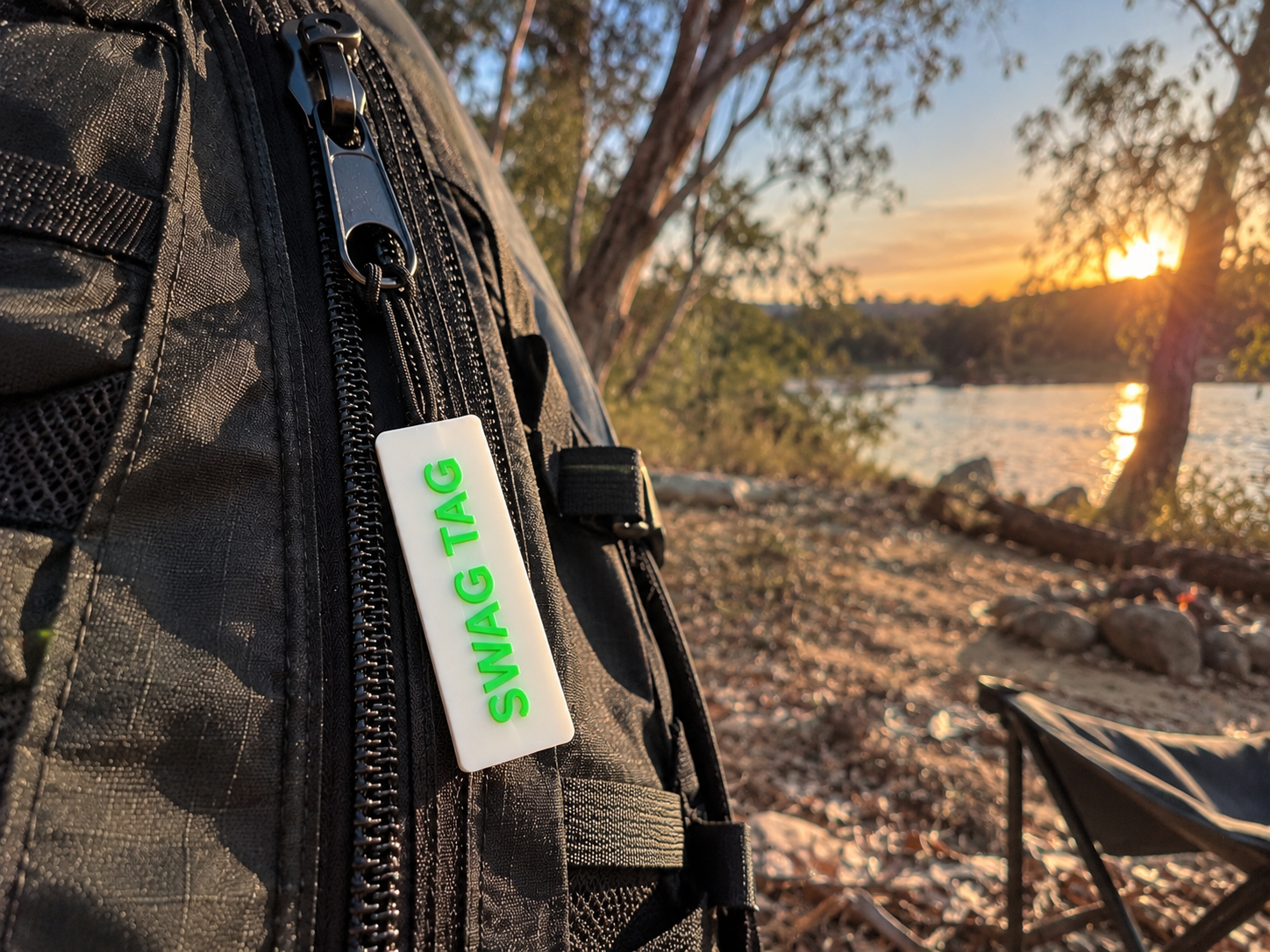 SwagTag on backpack at lakeside campsite at sunset