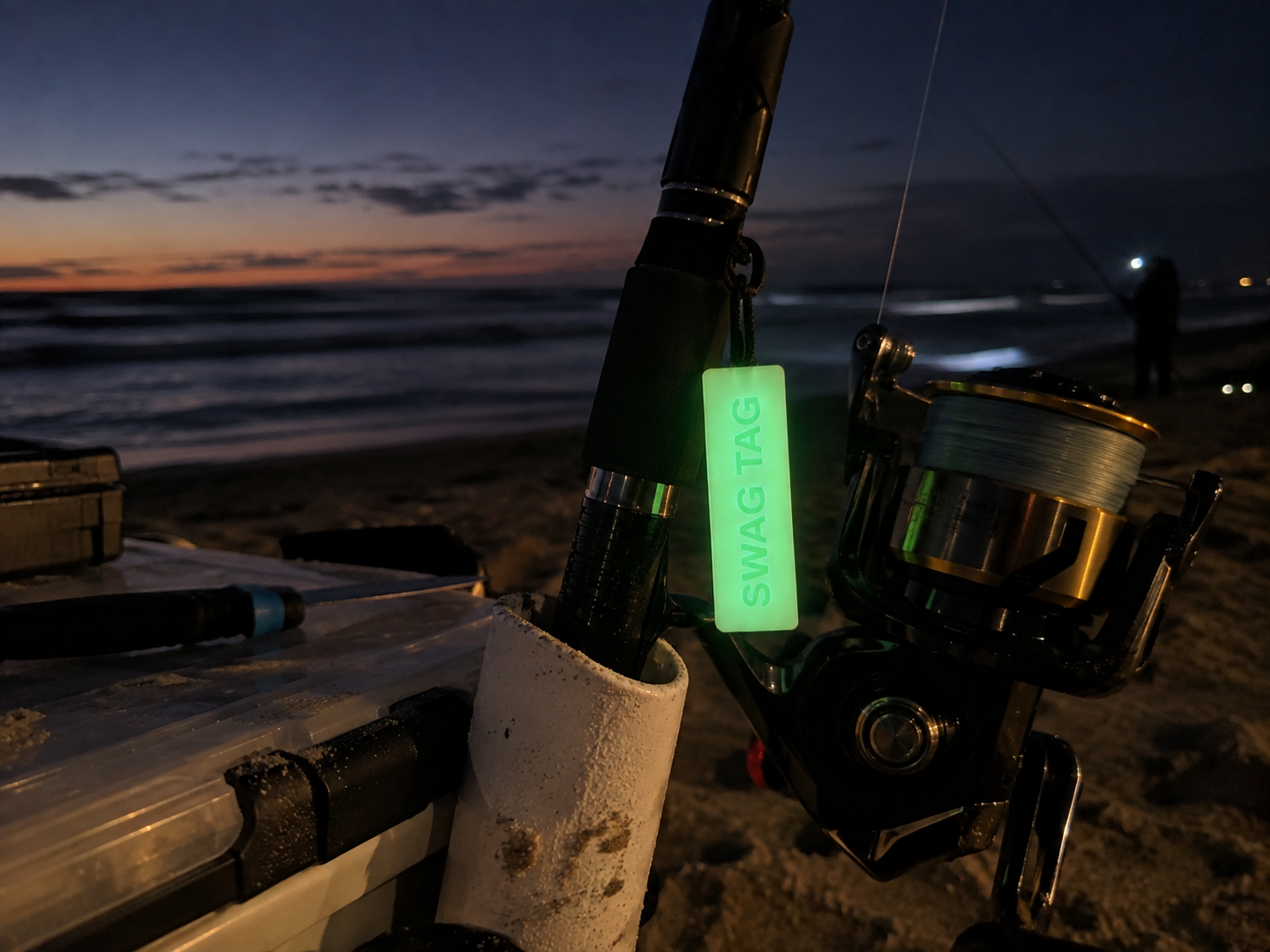 SwagTag glowing on fishing rod reel at the beach at dusk